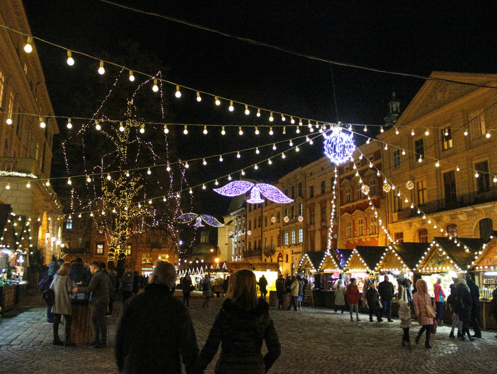 Christmas market stalls under strings of lights in a European town square